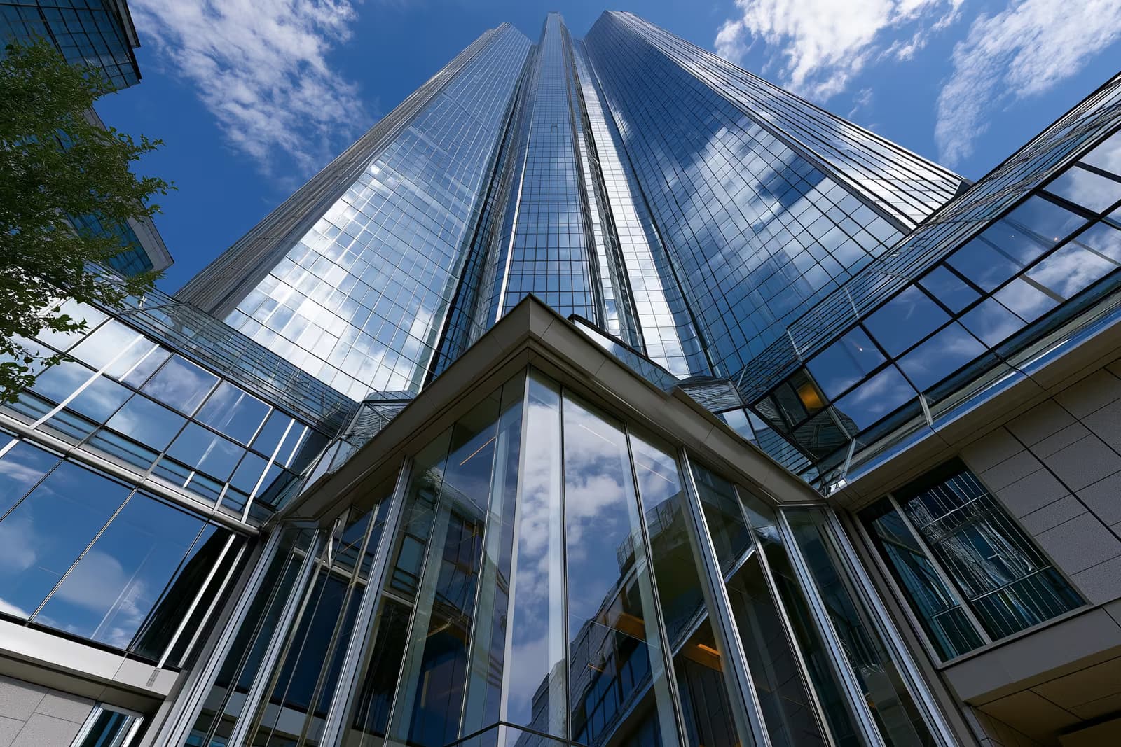 Ein moderner gläserner Bankturm in einem deutschen Finanzviertel unter klarem Himmel.