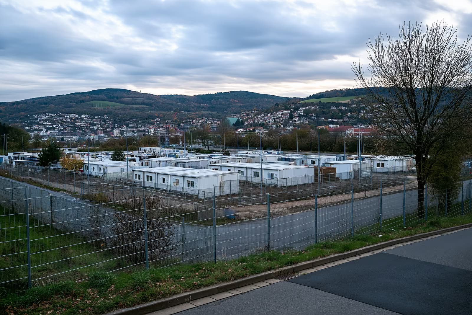 Eine umzäunte Wohnanlage mit Containergebäuden am Rande einer deutschen Stadt.