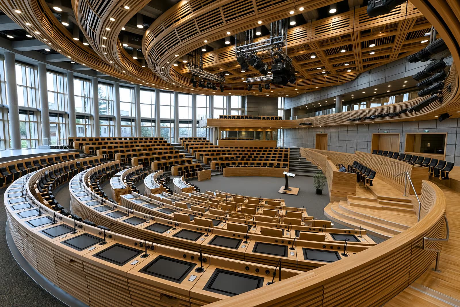 Weitläufiger Innenraum eines leeren Plenarsaals des nationalen Parlaments vor einer Debatte.