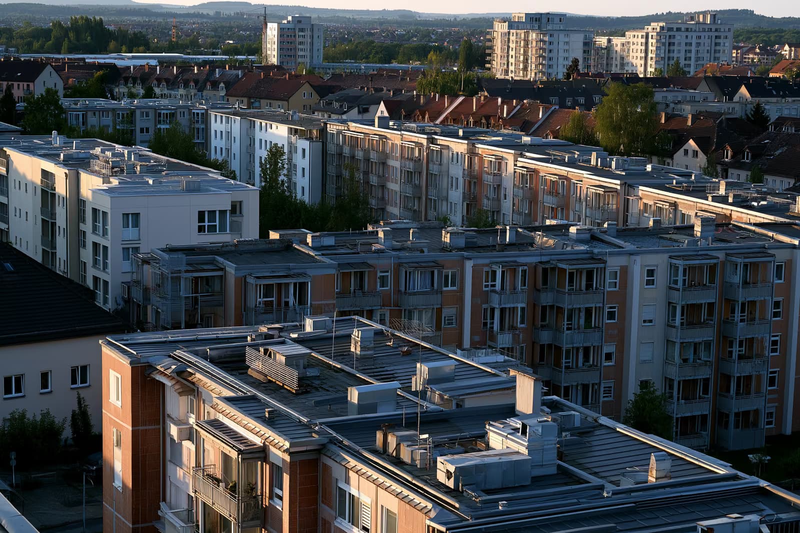 Dächer und Heizungsanlagen an Wohnhäusern in einer deutschen Stadt im warmen Nachmittagslicht.
